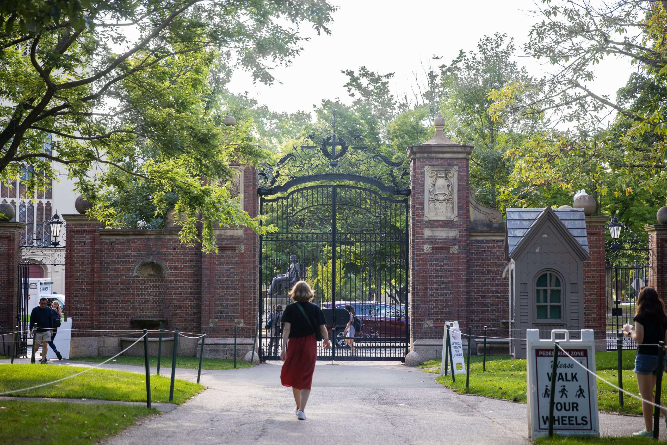 A woman walks towards a gate at Harvard University.
