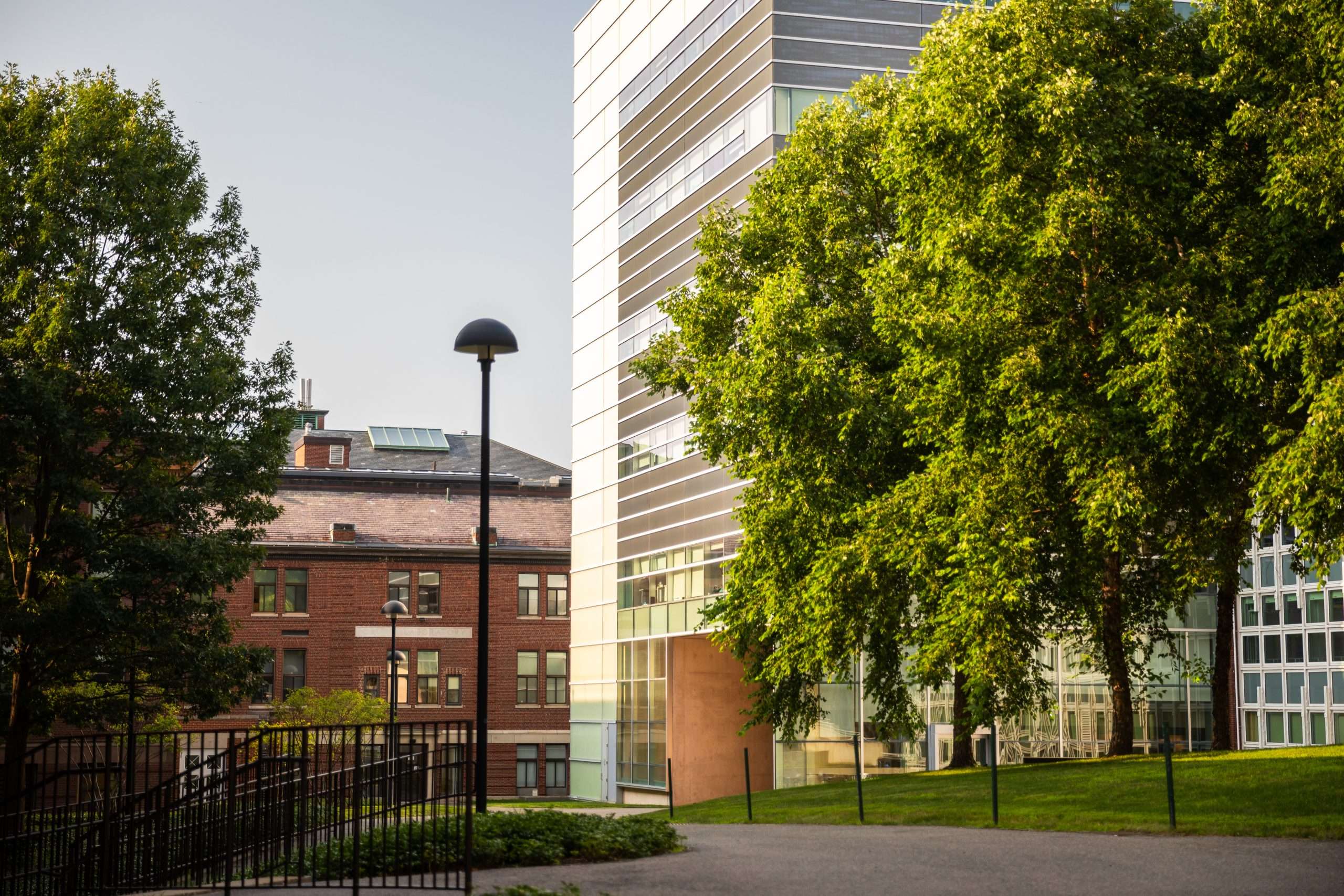 A glass building sits in front of a brick building on Harvard University's campus.
