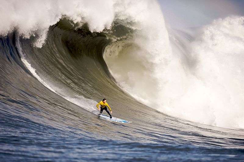 This is a portrait of a surfer riding a huge wave.