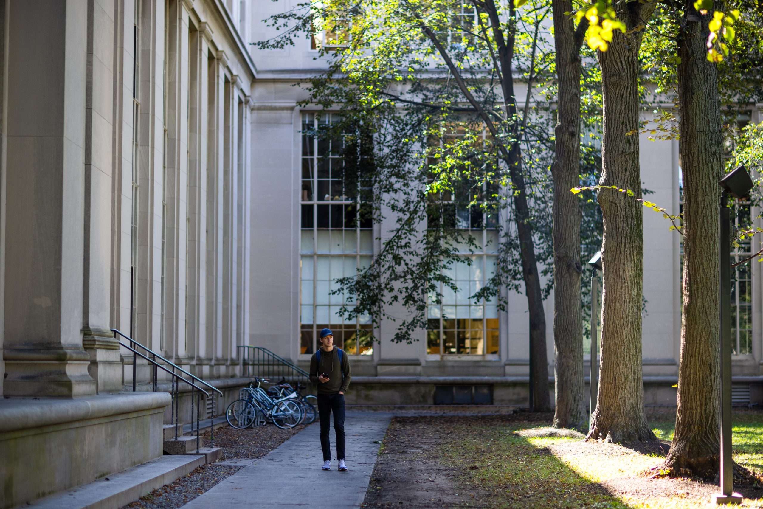 A person stands outside a columned building at the Massachusetts Institute of Technology.