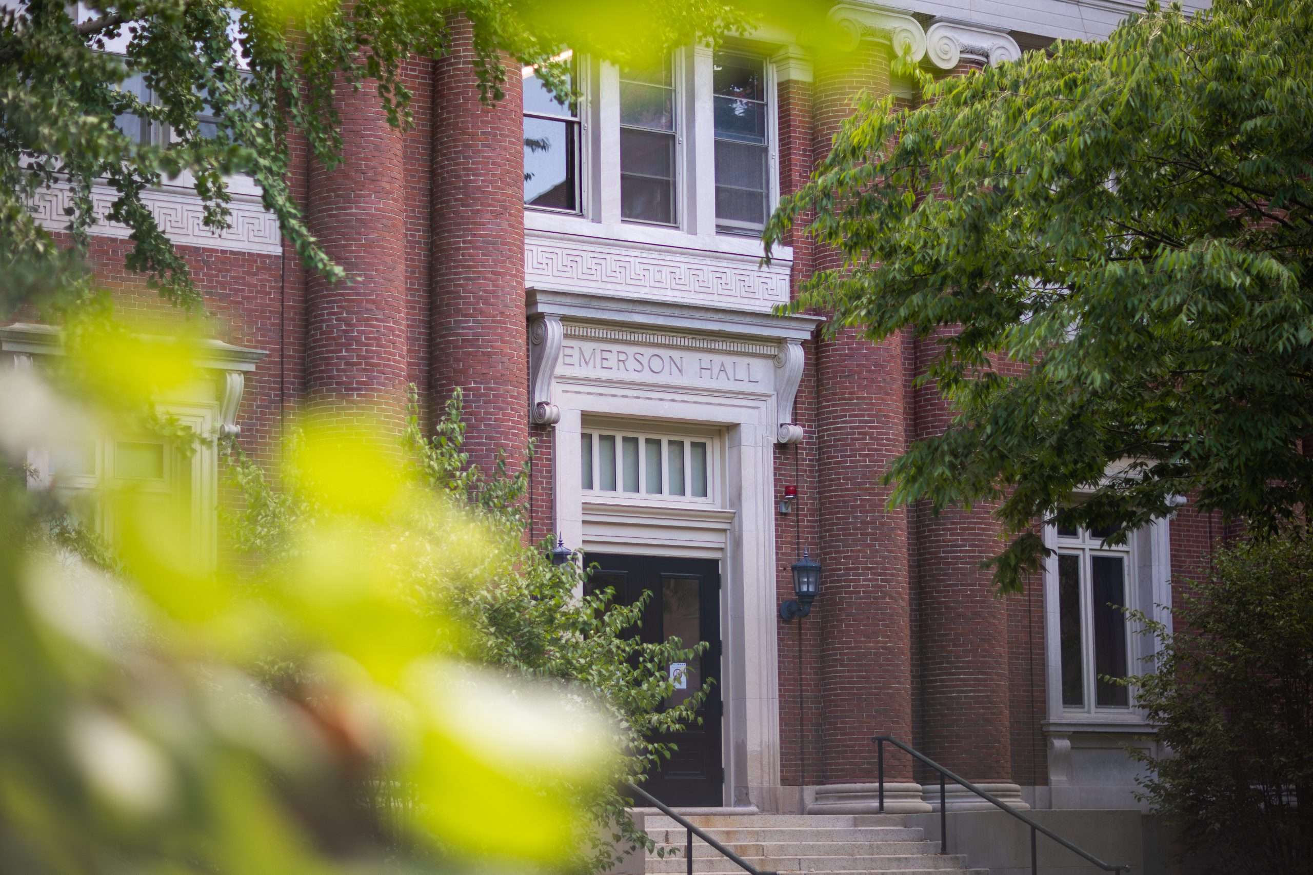 Emerson Hall is visible beyond a bush at Harvard University.