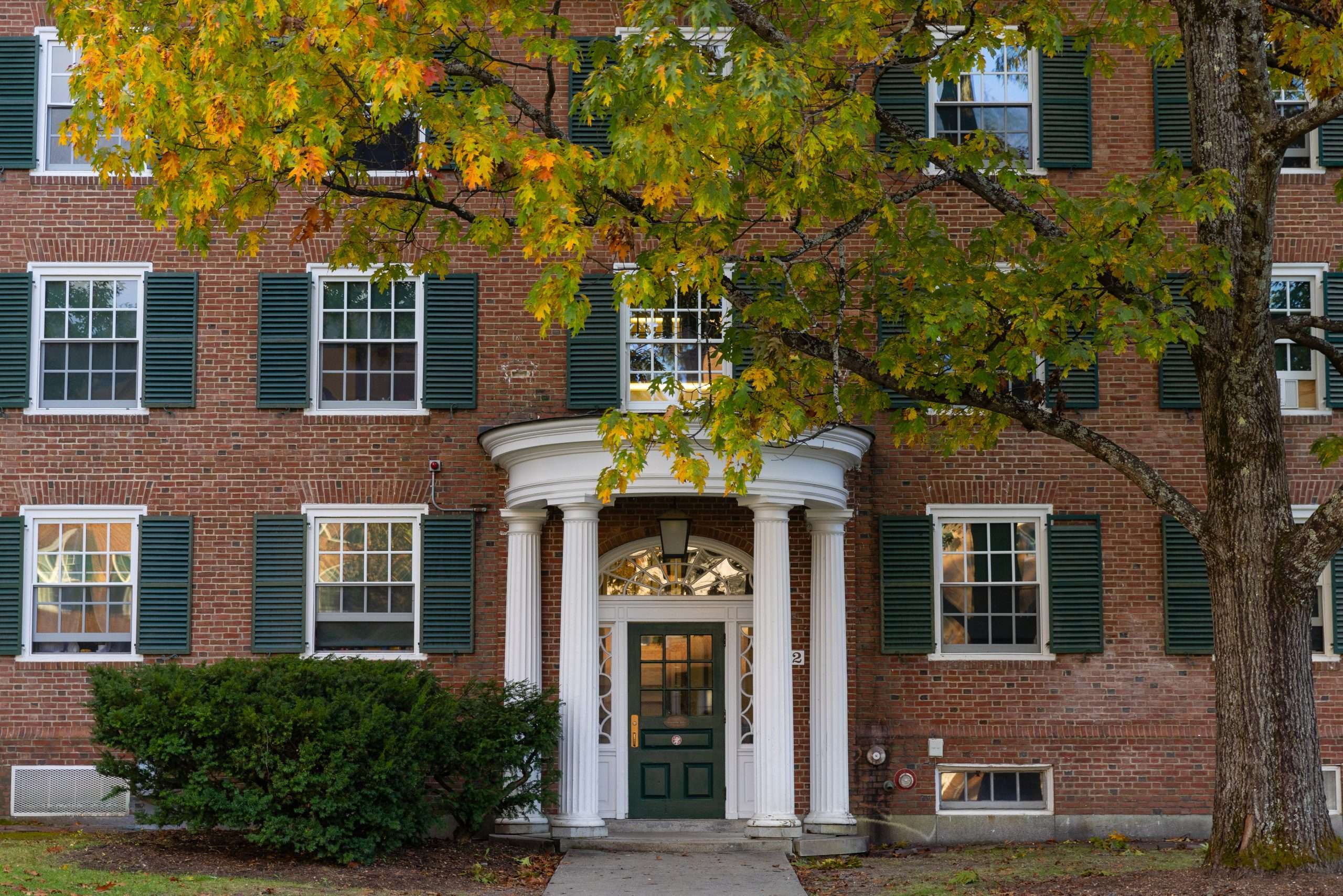 A brick building with green shutters is featured at Dartmouth College.