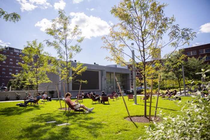 Students read on chairs on a lawn outside a building at the Massachusetts Institute of Technology.