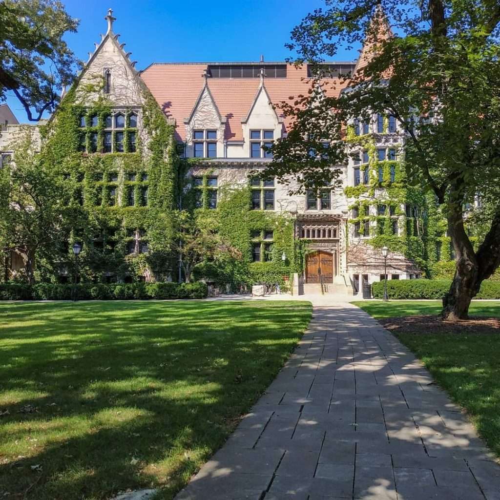 A castle-like building covered in ivy sits beyond a green lawn at the University of Chicago.
