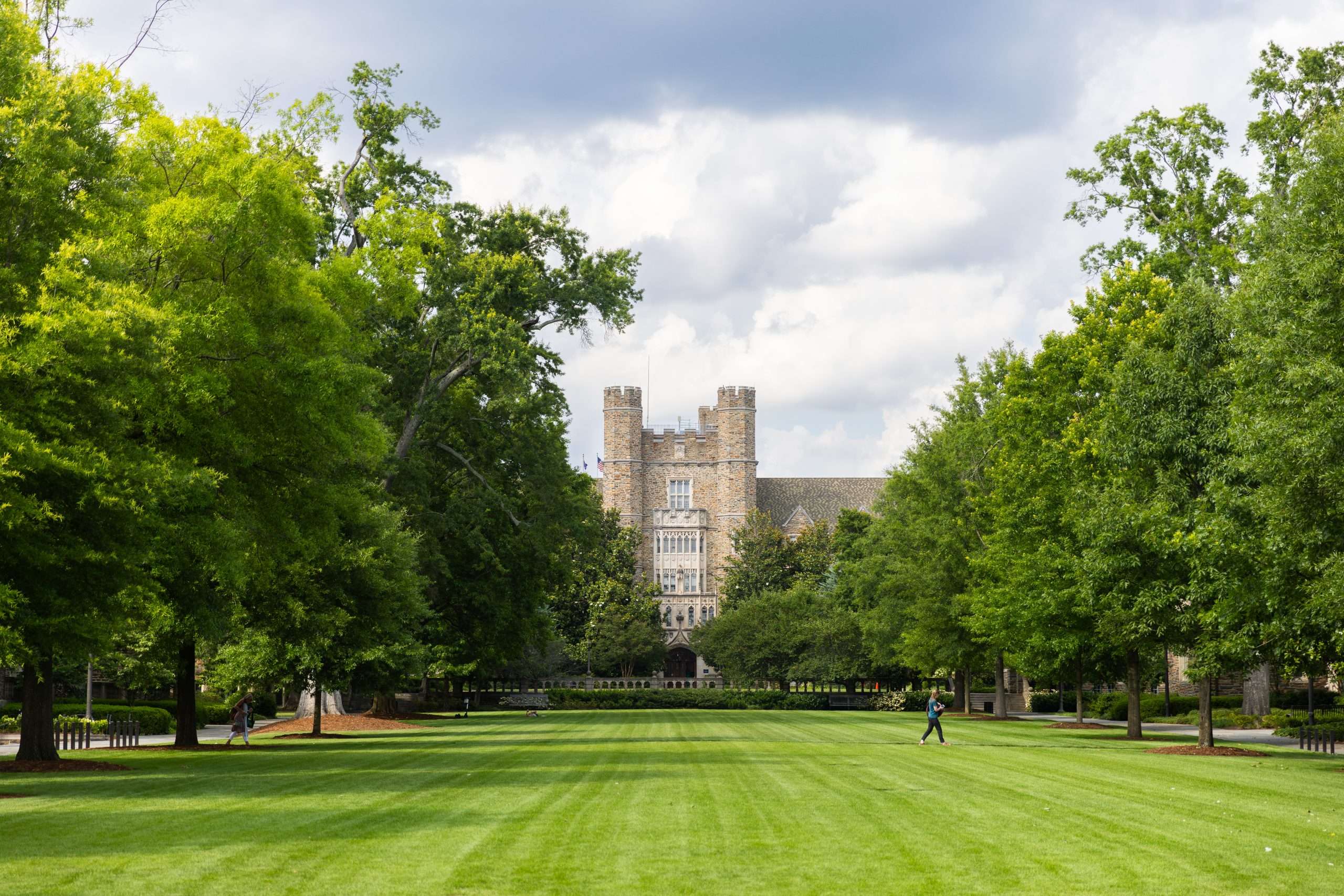 A person walks on a well-manicured lawn at Duke University.