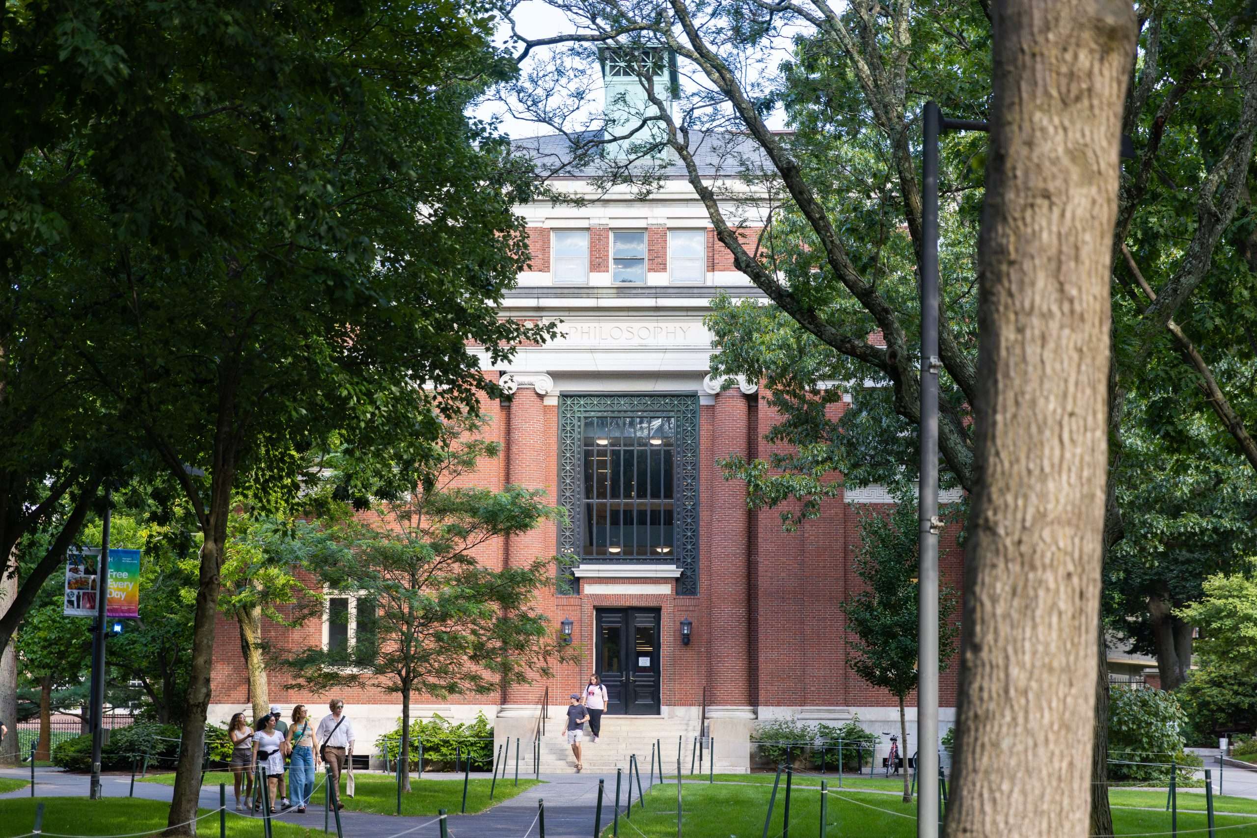 Students walk down the steps of a brick building at Harvard University.