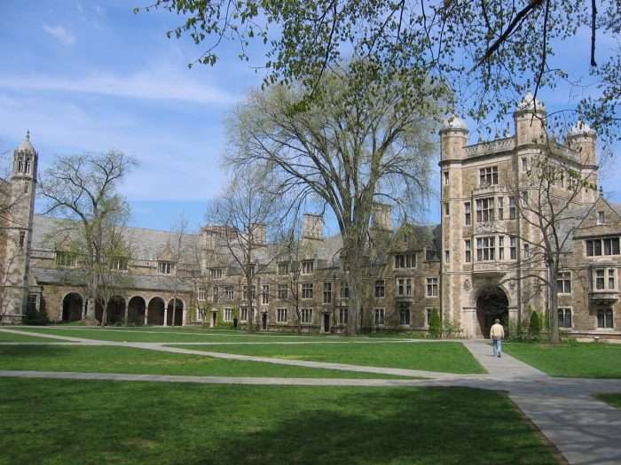 A panoramic of the University of Michigan campus, featuring a lawn and building.