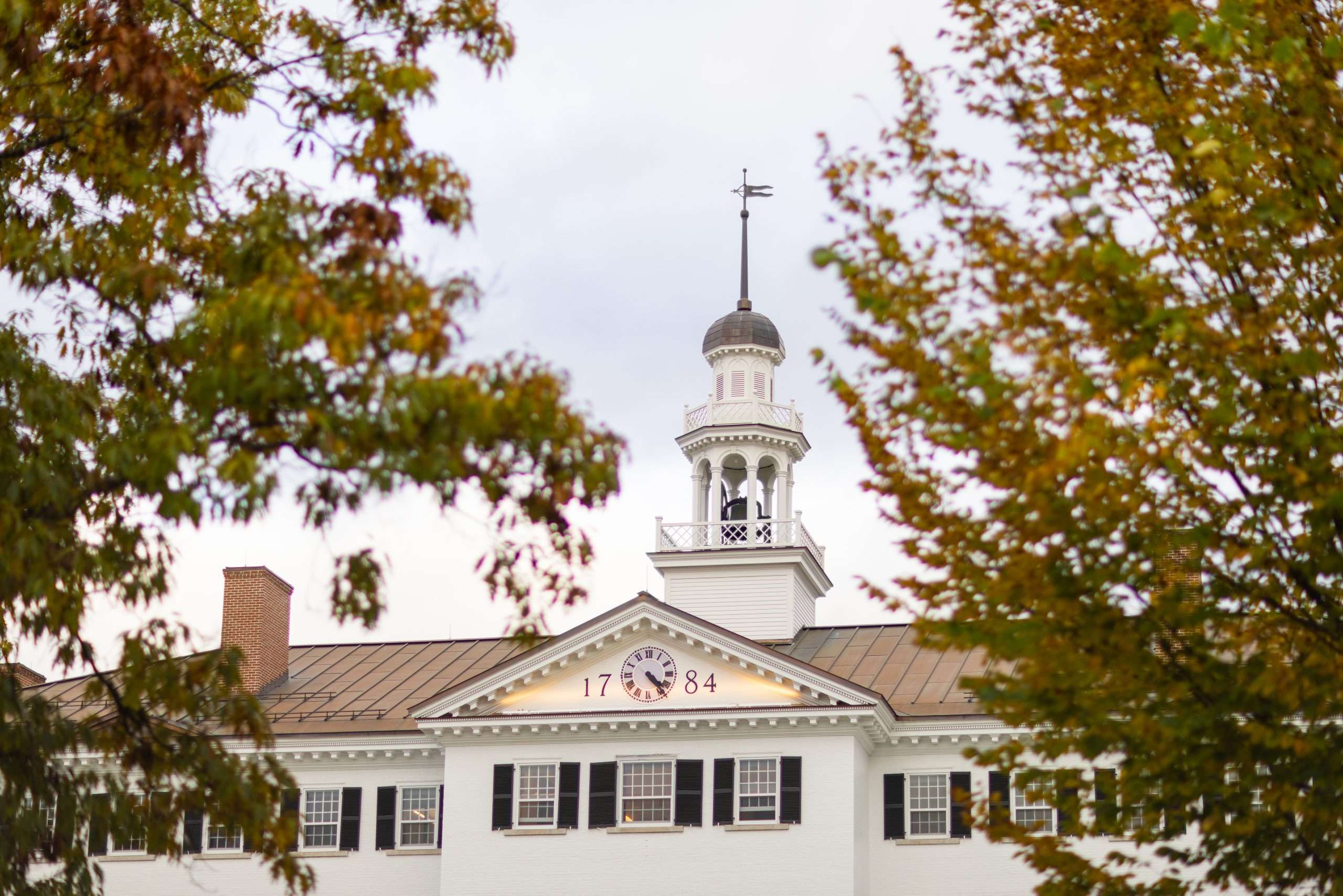 The weather vane is seen above the white-bricked Dartmouth Hall at Dartmouth College.